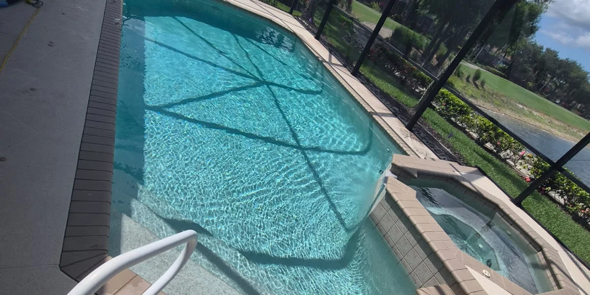 Before: a screened pool and spa overlooking a golf course lake, with brown bullnose brick coping, no waterline tile band and a dated interior finish