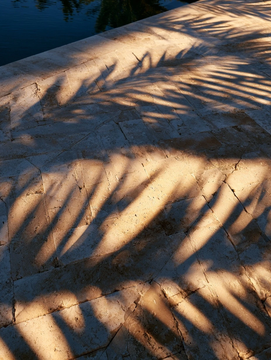 Travertine pool deck laid in a herringbone pattern beside blue water